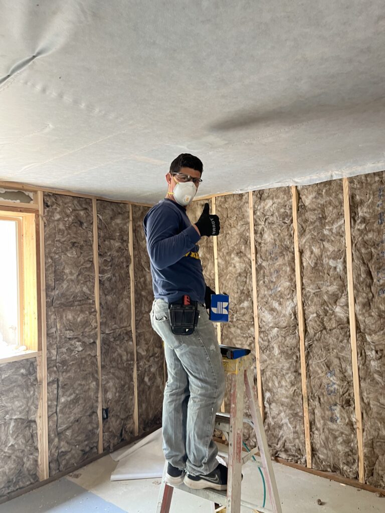 Installer placing insulation in the open framing of a residential construction project