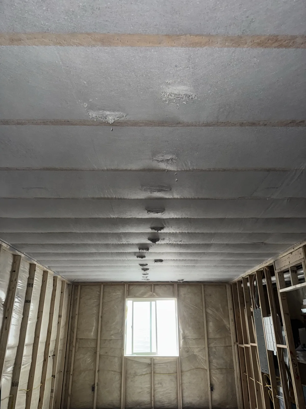 Completed basement ceiling insulation spanning the full open-framed room