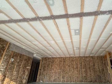 Netted insulation installed across an open basement ceiling before drywall