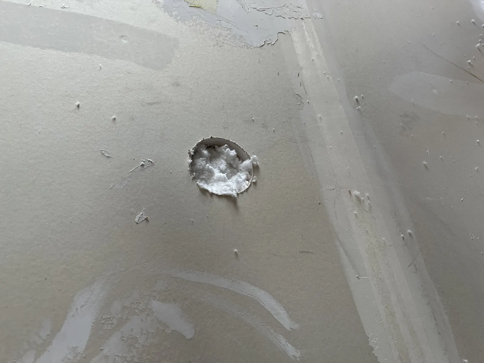 Close view of a drill-and-fill wall opening with insulation visible