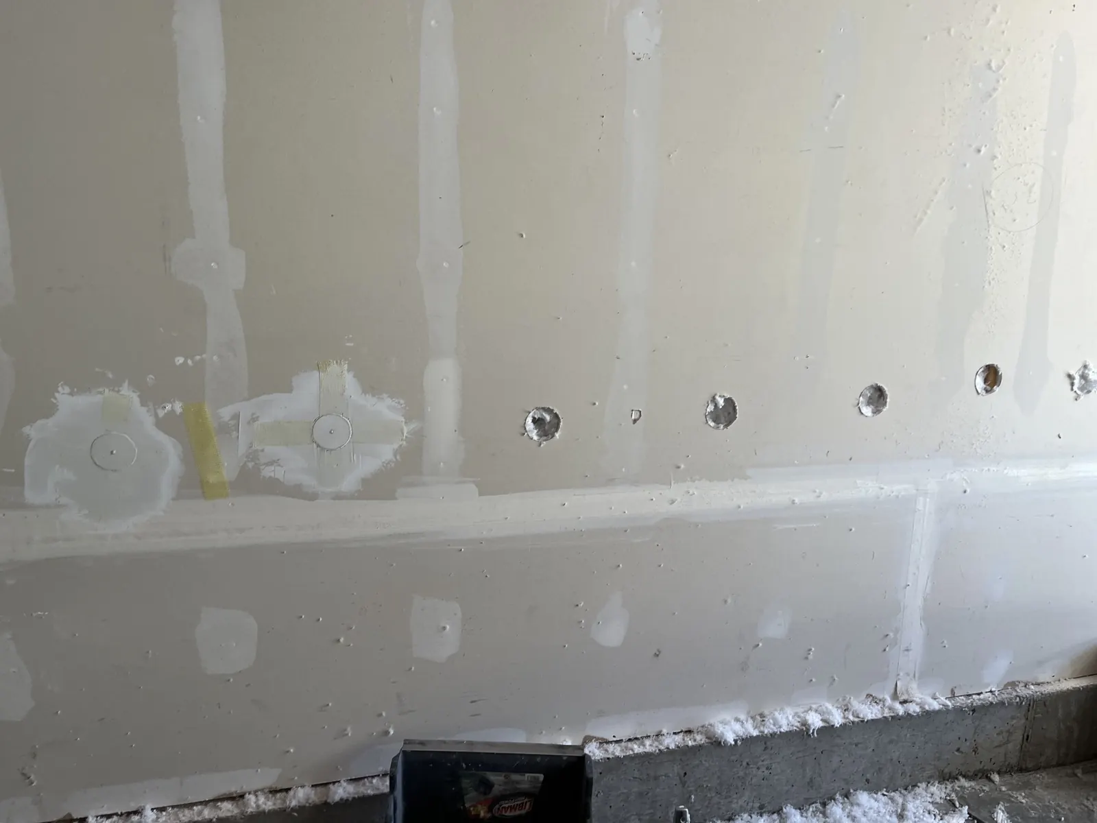 A planned row of drill-and-fill access openings in a finished wall