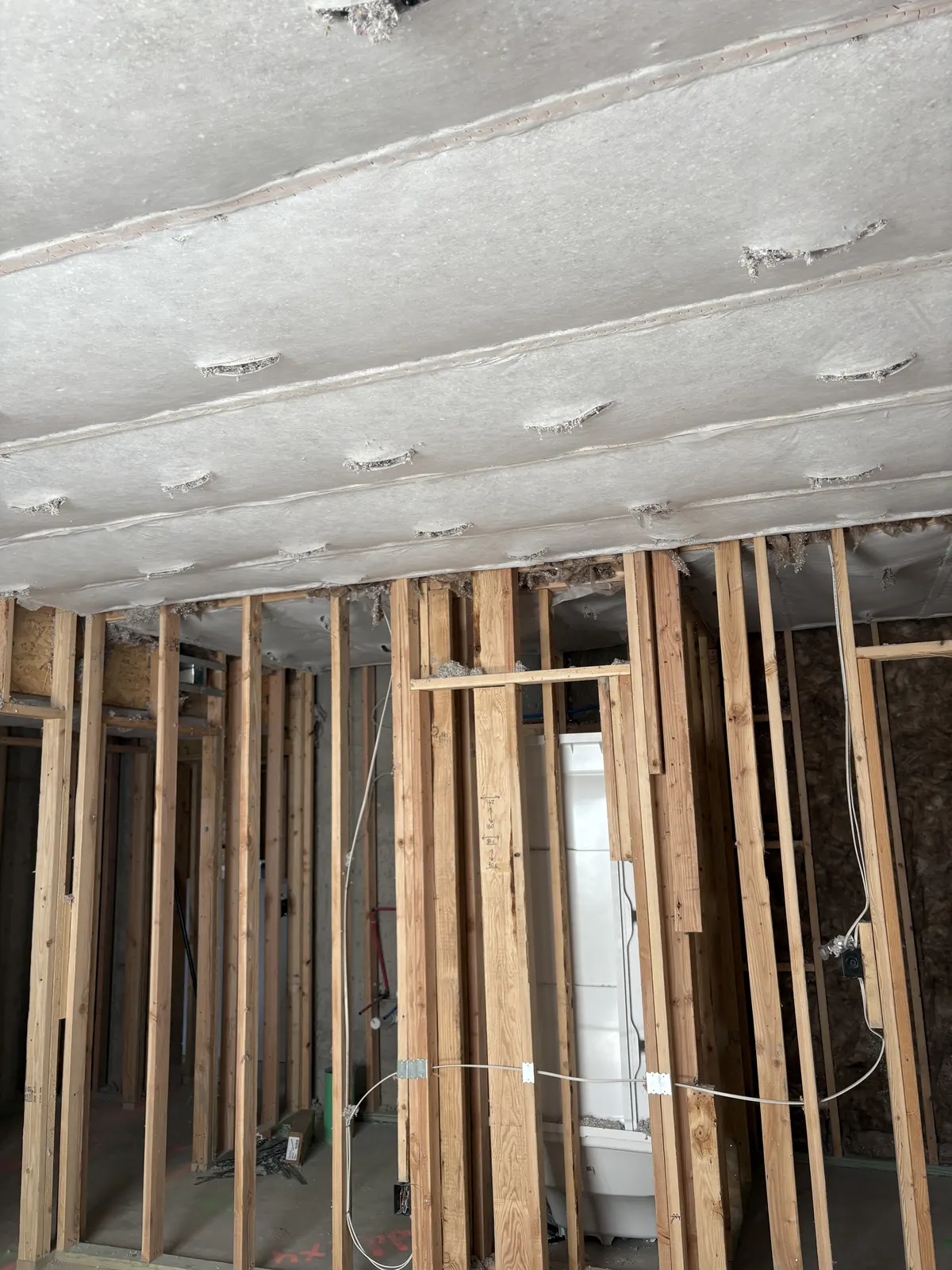 Netting secured across basement ceiling joists for blown insulation