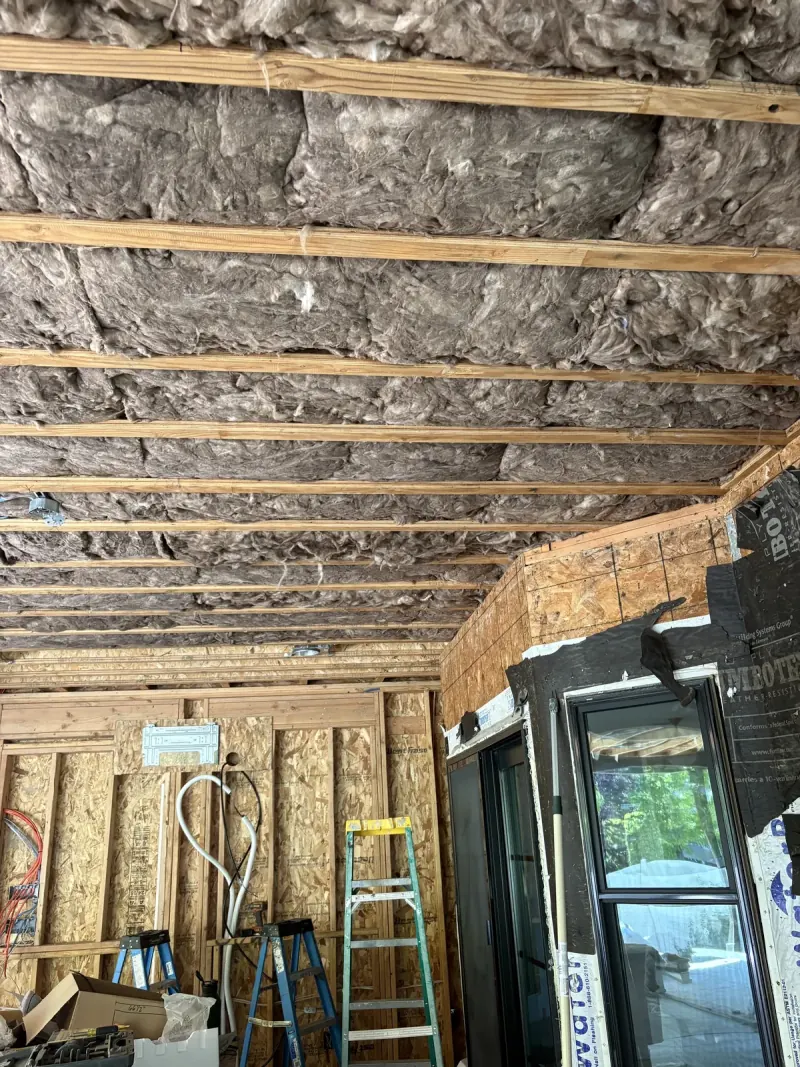 Insulated ceiling above open residential wall framing during construction