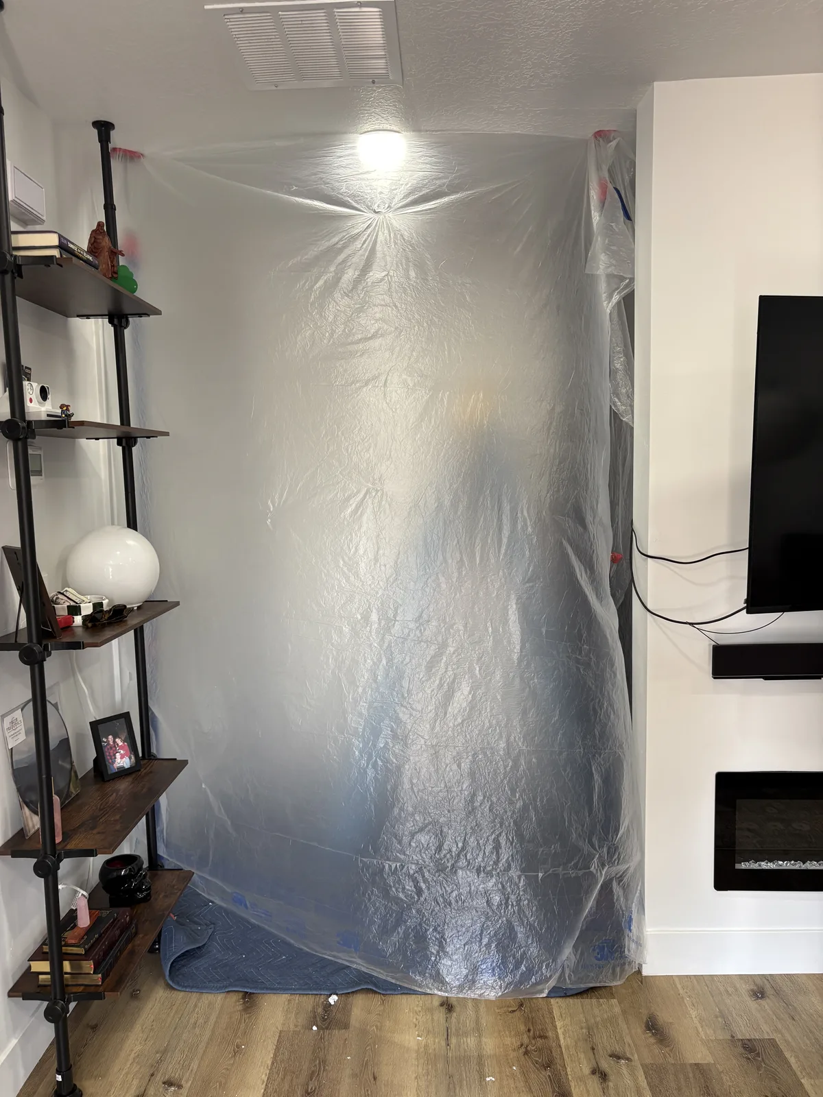 Living room sealed with plastic sheeting and floor protection before insulation work